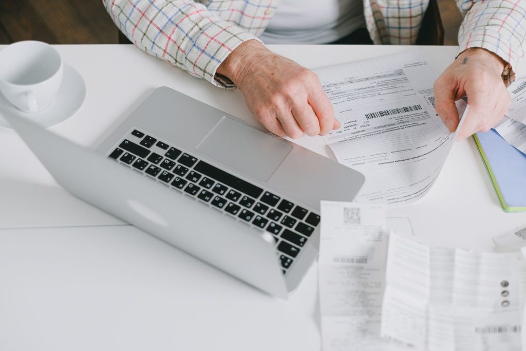 A person reviewing financial documents beside a laptop