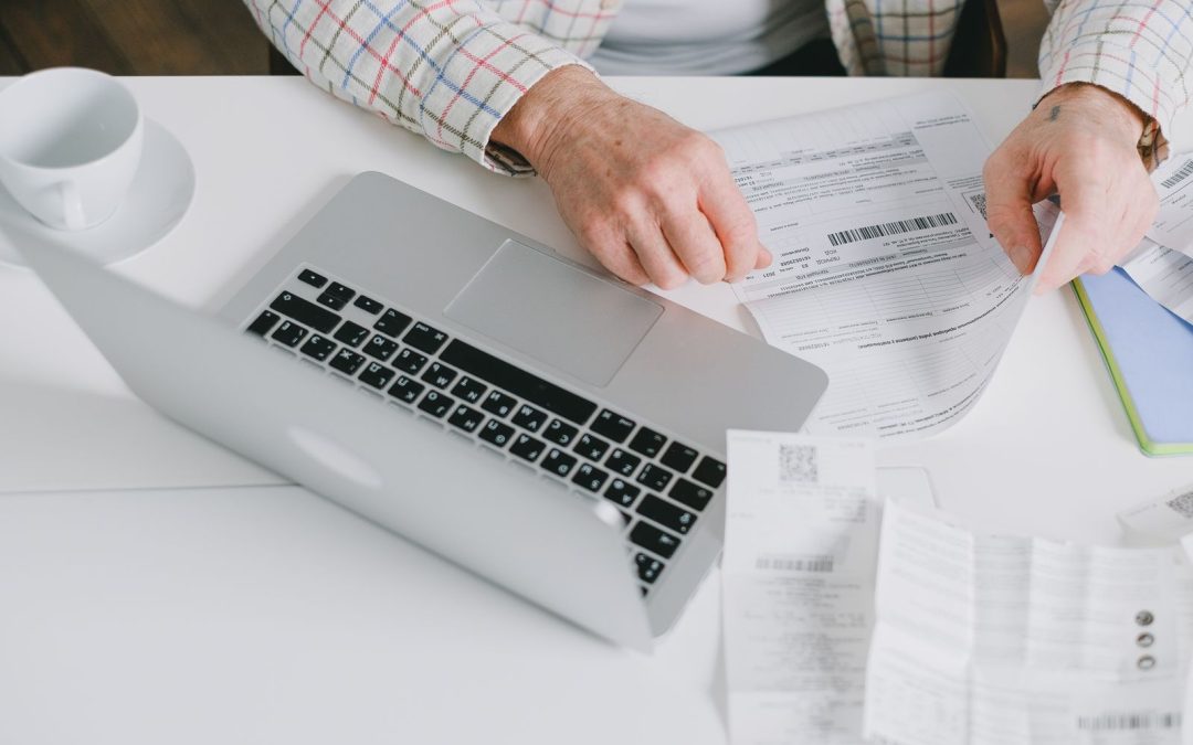 A person reviewing financial documents beside a laptop
